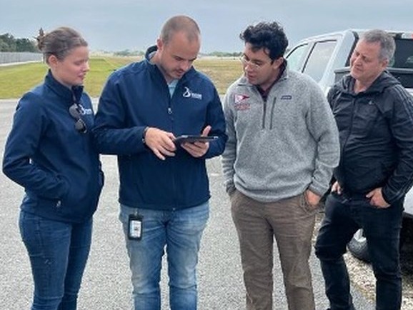 The EPIC and Simplify i3 team gathered around a tablet during a field training session at an airport